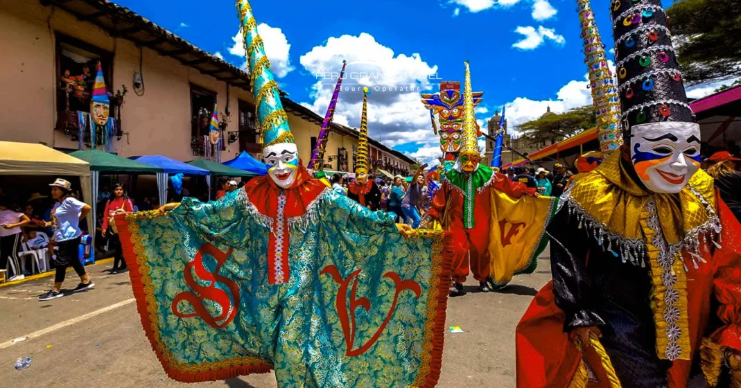 Carnaval en Perú con desfile en Cajamarca y artistas enmascarados con sombreros altos y capas coloridas bailando por una calle llena de gente
