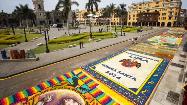 Plaza Mayor de Lima decorada con alfombras de aserrín que dicen “Semana Santa 2024”, palmeras y edificios coloniales al fondo.