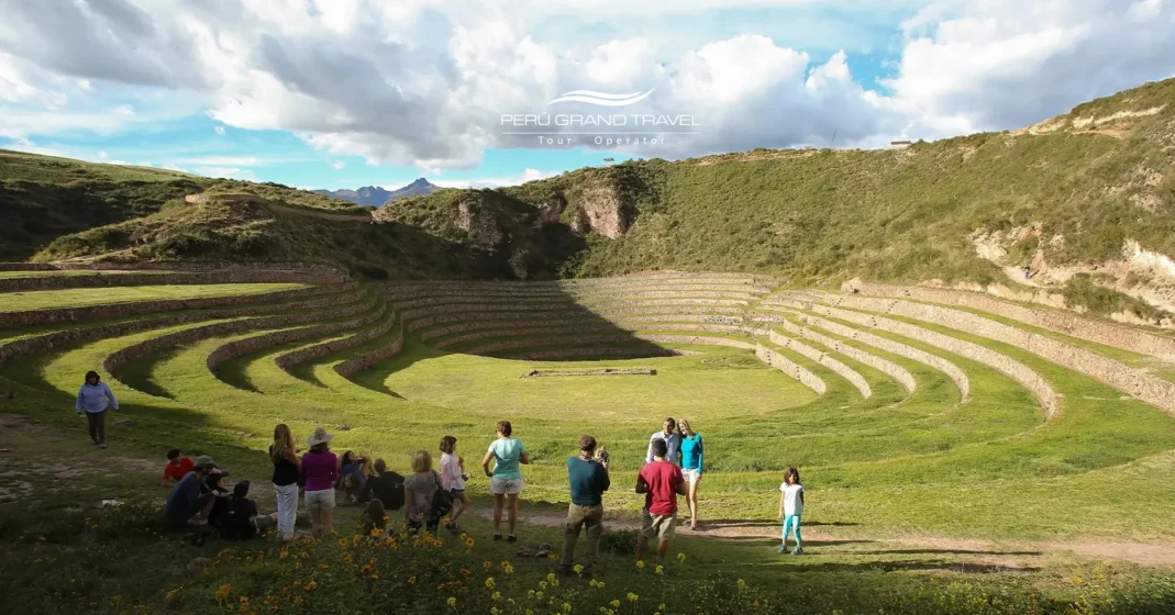 Tours de Medio Día en Perú en el sitio arqueológico de Moray, mostrando las terrazas circulares incas en el Valle Sagrado con visitantes explorando el antiguo complejo agrícola