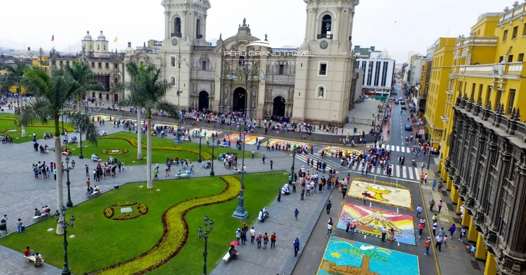 Tradiciones de Semana Santa en Perú: guía para viajeros 1 Vista de la Plaza Mayor de Lima y su Catedral, con alfombras coloridas de Semana Santa sobre la calle y personas caminando cerca.