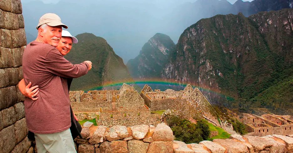 Los Mejores Circuitos Machu Picchu: Descúbrelo aquí 7 adultos mayores en machu picchu con vista de las construcciones incas y un arcoiris