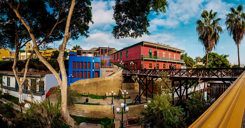 Qué visitar en Lima: lo mejor de la ciudad 5 vista del distrito de barranco psando por el puente de los supiros, edificios de colores y vegetacion alrededor
