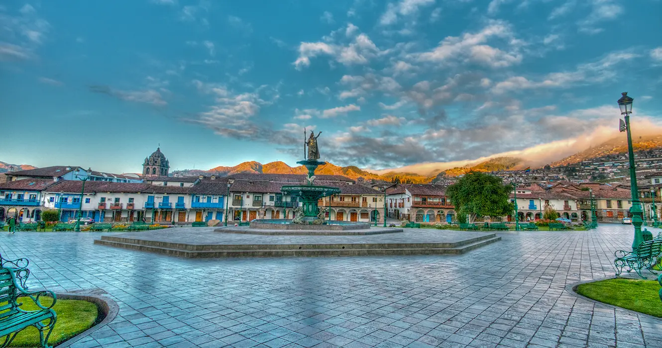 Plaza de armas el centro principal, con vistas de balcones y un cielo celeste despejado y la estatua inca en el medio de la plaza