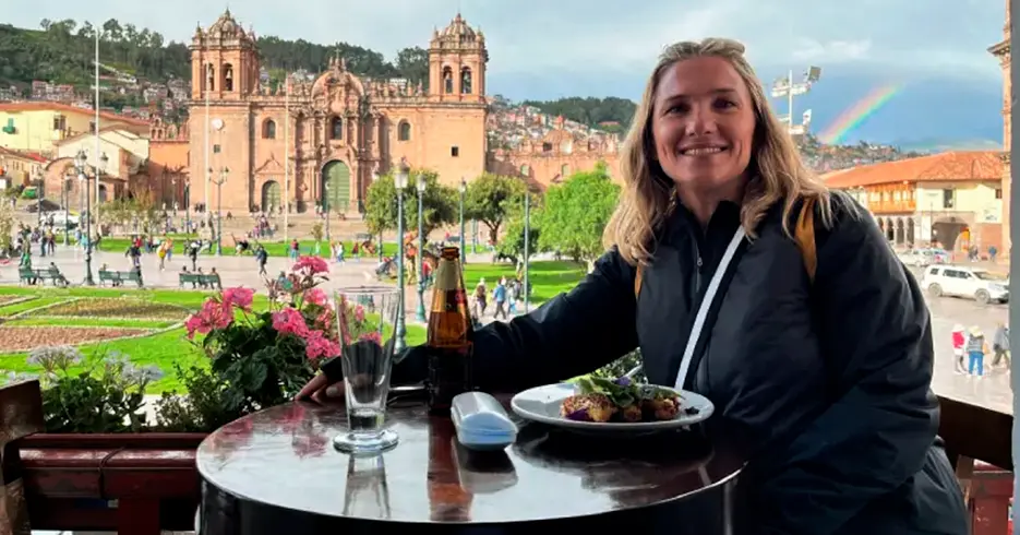 turista comiendo con vista de la palza de armas de cusco