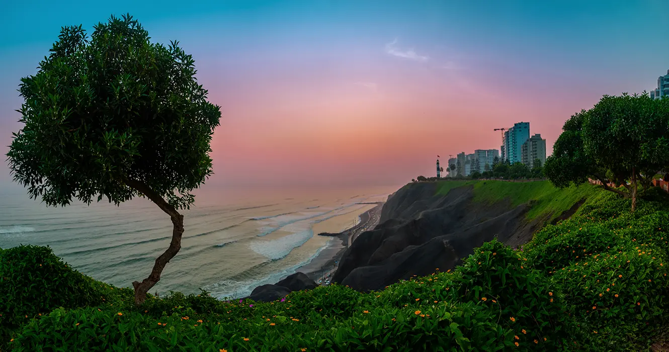 Lima en un atardecer con la vista del malecón de Miraflores, la vista del océano pacífico y mucha vegetación verde