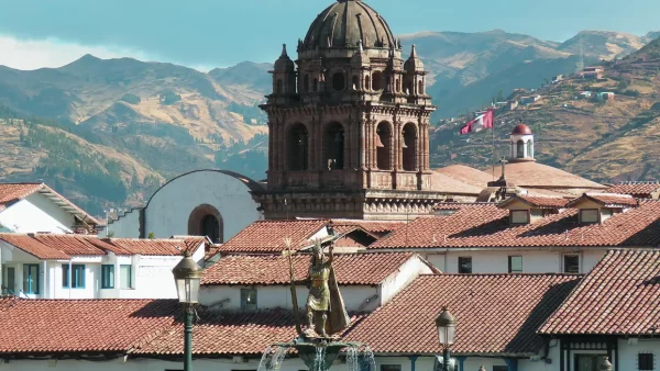 Vista del inca en el medio de la plaza de armas de cusco, la iglesia de la merced de fondo y techos de las casonas cusqueñas