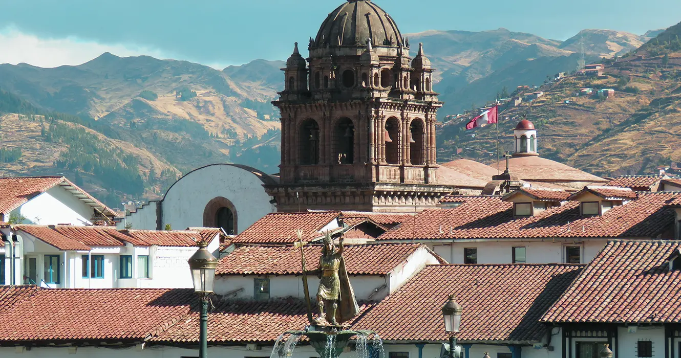Vista del inca en el medio de la plaza de armas de cusco, la iglesia de la merced de fondo y techos de las casonas cusqueñas