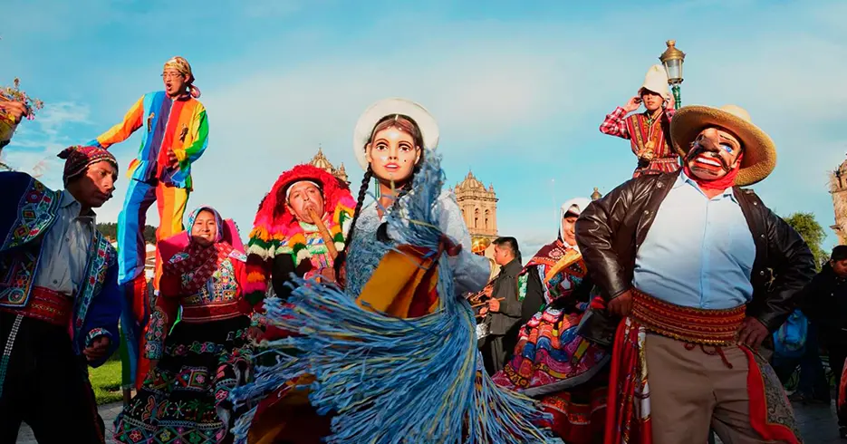Fiestas en cusco, danzas típicas de cusco, mujer bailando con una máscara y hombres bailando con sus trajes típicos y uno con una máscara