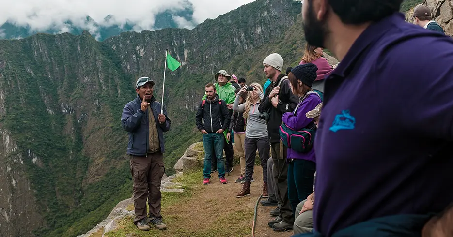 guia oficial de turismo en machu picchu explicando y turistas escuchando