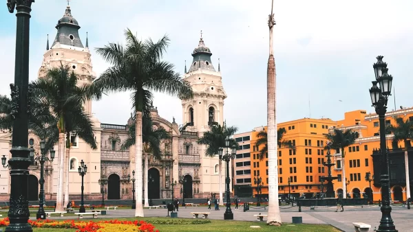 Lima la capital de Perú, específicamente en la plaza de armas, con la vista de la catedral y el palacio municipal, con vista de palmeras y un cielo despejado.