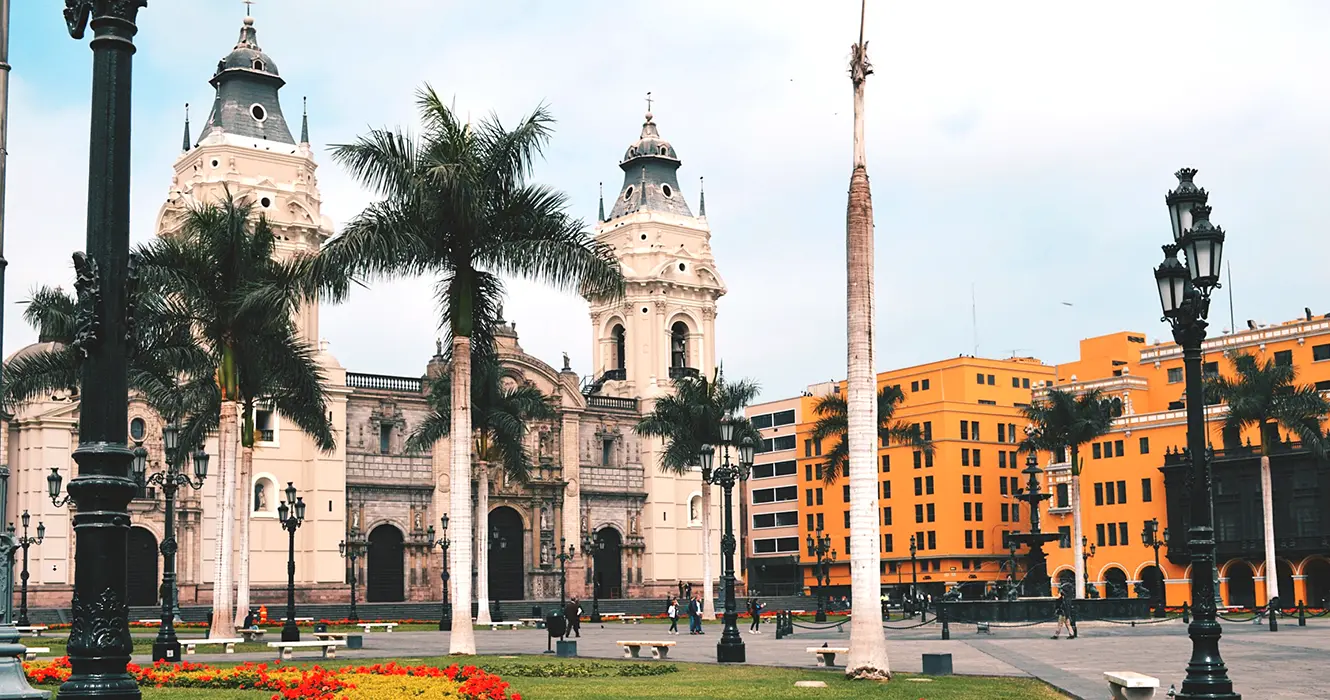 ¿Qué Ver en Perú 9 Días? Los Imperdibles del País 7 Lima la capital de Perú, específicamente en la plaza de armas, con la vista de la catedral y el palacio municipal, con vista de palmeras y un cielo despejado.