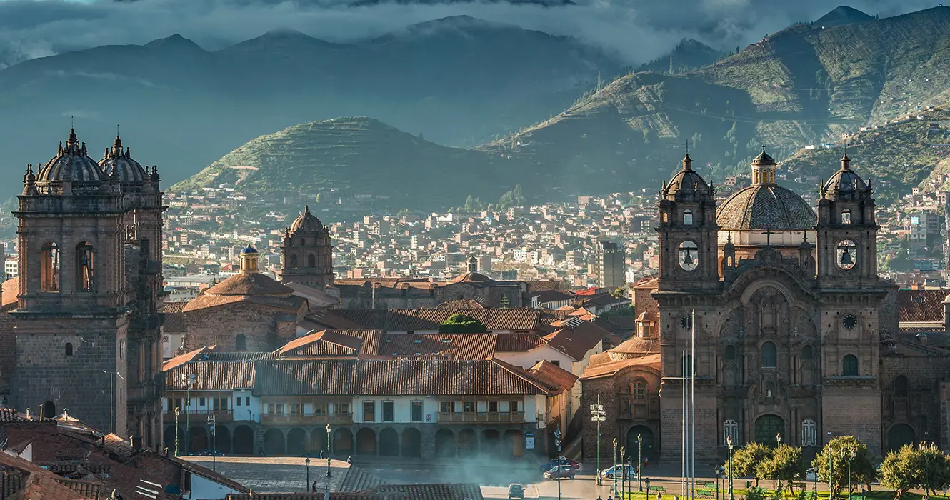 La ciudad de cusco, en que lugares puedo visitar en Perú, vista de la catedral y la iglesia de la compañía de Jesús, y atrás las casas y edificios de cusco