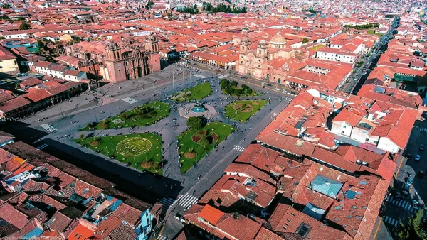 La plaza de armas de cusco, desde el cielo en dron, se ven las 3 iglesias, la catedral, la compañía de Jesús y la sagrada familia de Jesús con los jardines verdes de la palza de armas