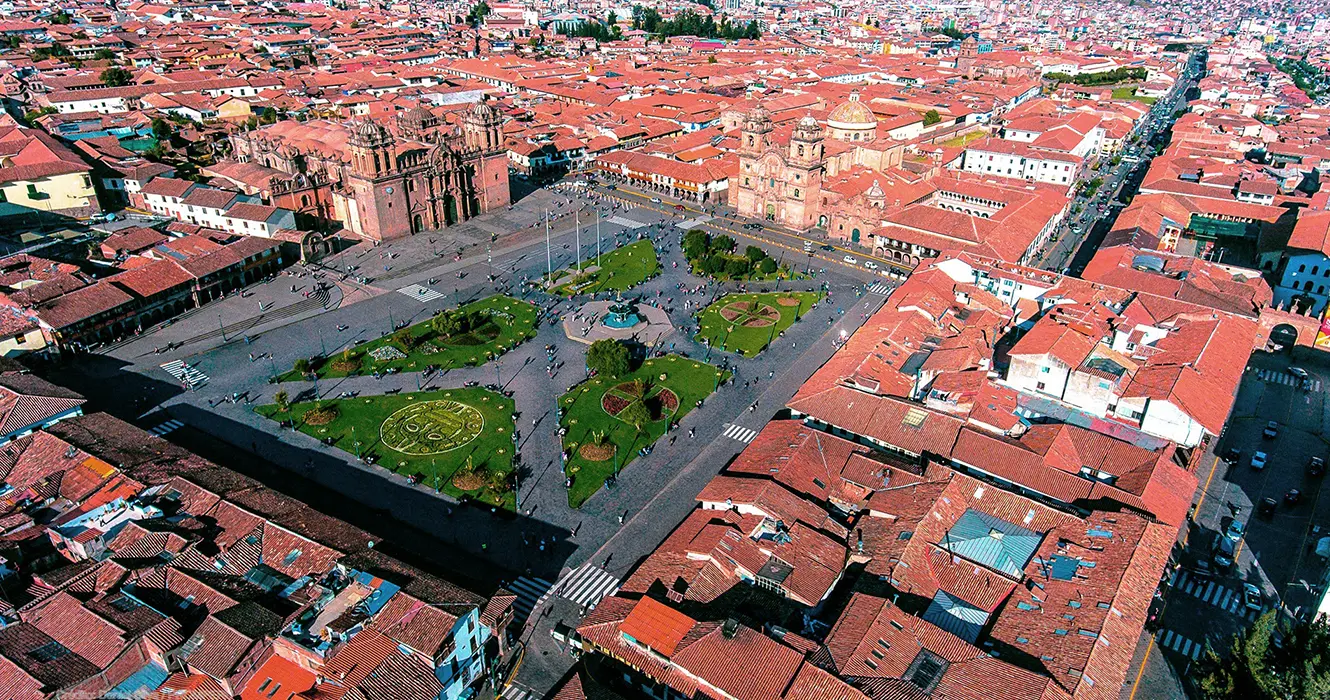 Tour cusco y Machu Picchu 3 Días: Un Viaje Inolvidable a la Ciudad Perdida 1 La plaza de armas de cusco, desde el cielo en dron, se ven las 3 iglesias, la catedral, la compañía de Jesús y la sagrada familia de Jesús con los jardines verdes de la palza de armas