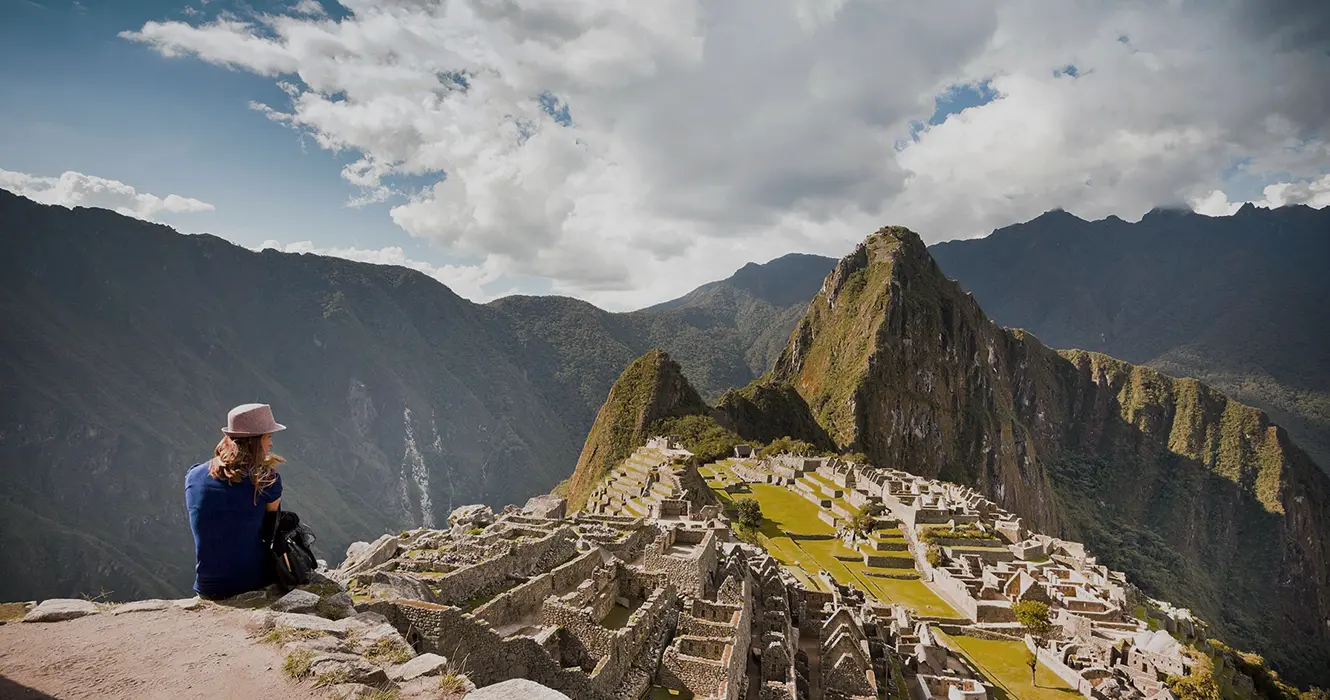 Turista sentada observando la vista espectacular que se tiene de Machu Picchu