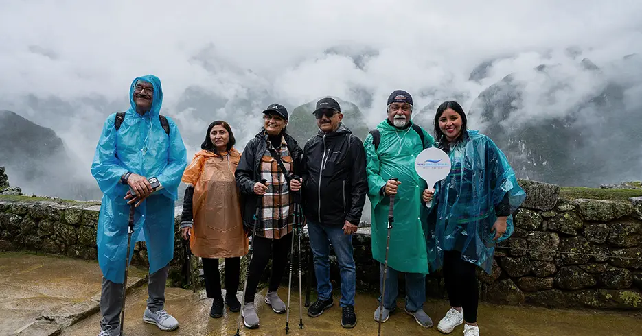 Qué ropa llevar a Machu Picchu, turistas en la lluvia de Machu Picchu con ponchos de lluvia y las montañas tapadas con la niebla