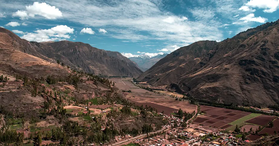 Vista del valle sagrado en cusco, con paisaje lleno de montarlas y árboles, un cielo despejado y celeste