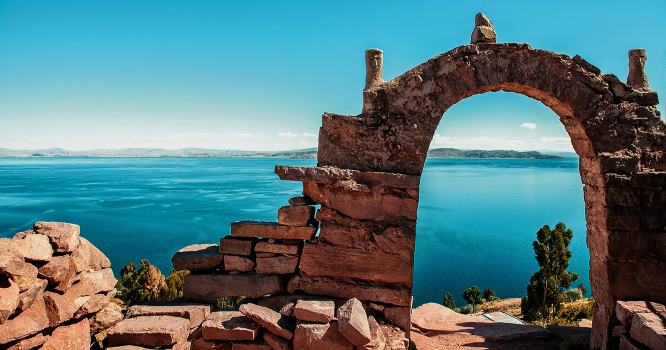 Lugares para visitar en Puno Perú: Explora lo Mejor con Nosotros 5 Arco rocoso de la isla taquile en puno con una vista amplia del lago Titicaca y un cielo turquesa parecido al lago Titicaca